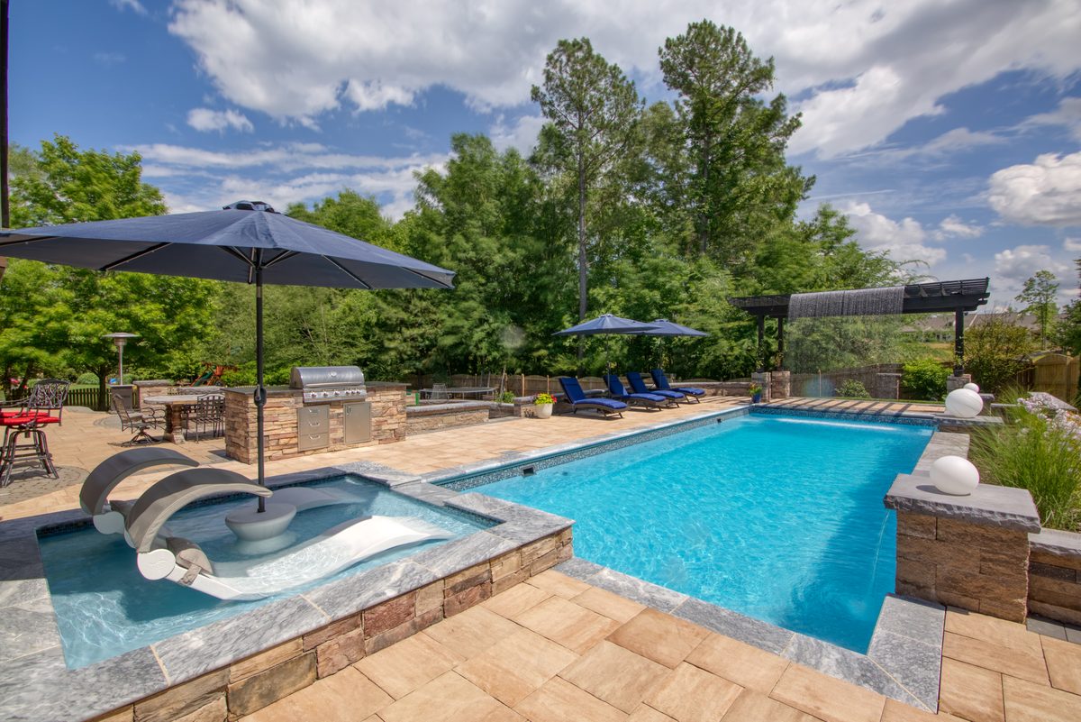 Fiberglass pool with tanning ledge and color lighting at dusk